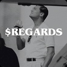 a black and white photo of a man holding a glass of wine with the words $ regards behind him