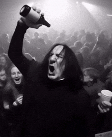 a man with long hair is holding a beer bottle in the air