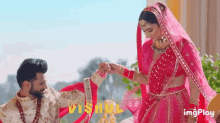 a bride and groom are posing for a picture and the bride is putting a ring on the man 's finger .