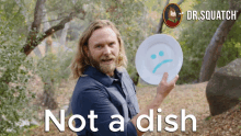 a man is holding a plate with a sad face on it and the words not a dish behind him