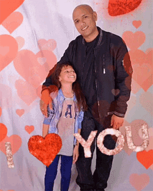 a man and a little girl are posing for a picture with hearts in the background and a sign that says " i love you "