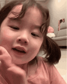 a little girl is making a funny face while sitting on the floor in a living room .