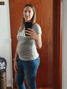 a pregnant woman taking a selfie with her phone