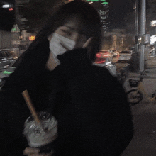 a woman wearing a mask is holding a cup of milkshake