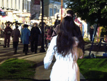 a woman in a white coat walks down a sidewalk in front of a sign that says " day "