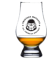 a glass of thirteen monkeys all american whiskey with a gorilla on it