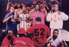 a man wearing a red shirt with the number 52 on it is surrounded by other men