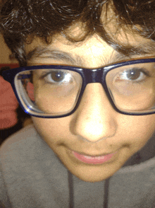 a boy wearing glasses looks at the camera