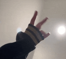 a person 's hand with a striped sleeve is making a devil horns gesture