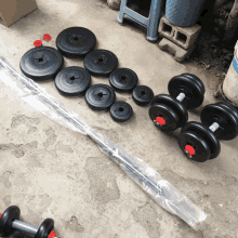 a set of dumbbells and barbells are sitting on a concrete surface