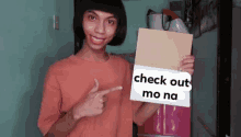 a young man is holding a sign that says `` check out mo na '' .