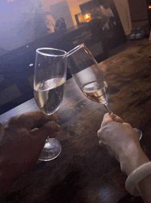 two people toasting with glasses of wine on a table