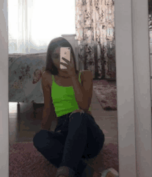 a woman in a neon green tank top is taking a picture of herself in the mirror