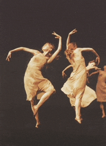 a group of women are dancing on a stage in a dark room