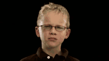 a young boy wearing glasses and a black shirt is making a funny face