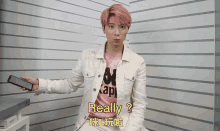 a man with pink hair is holding a cellphone and says really