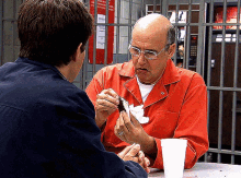 two men are sitting at a table in front of a vending machine that says ' vending machine ' on it