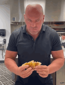 a bald man in a black shirt is holding a piece of food in front of a viking refrigerator