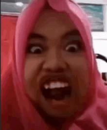 a woman wearing a pink hijab is making a funny face with her mouth open .