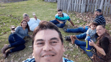 a group of people laying on the grass with one man holding a bottle