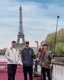 three men are posing in front of the eiffel tower