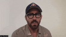 a man with a beard wearing glasses and a baseball cap with the name ryan reynolds on the bottom