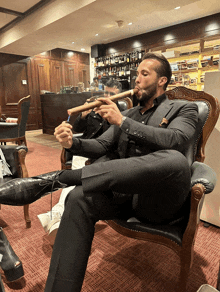 a man in a suit is smoking a cigar in a chair