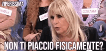 a woman with blonde hair is sitting in front of a group of women and says non ti piaccio fisicamente ?