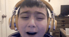 a young boy wearing headphones is making a funny face