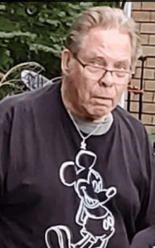 an elderly man wearing glasses and a mickey mouse shirt