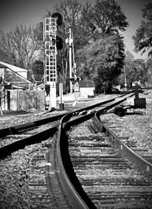 a black and white photo of a train track with a fence in the background