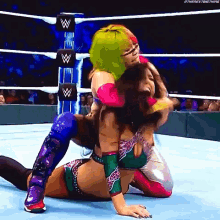 two women are wrestling in a wrestling ring and one of them is laying on the floor .