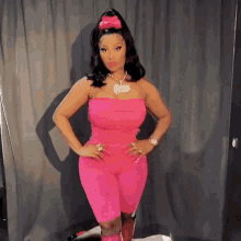 a woman wearing a pink jumpsuit and a necklace with the word nicki on it