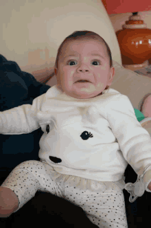 a baby wearing a white shirt with a bird on it is making a funny face