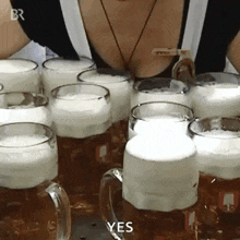 a woman is standing in front of a row of beer mugs with the words yes written on them .