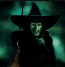 a witch holding a broom pointing at something