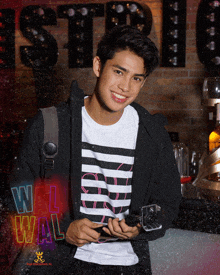 a young man holding a camera in front of a wall that says wal wal