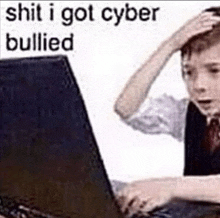 a boy is sitting in front of a laptop computer with his hand on his head and the words `` shit i got cyber bullied '' .