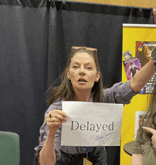 a woman holds a sign that says delayed