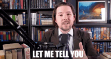 a man in a suit and tie is talking into a microphone and says " let me tell you "