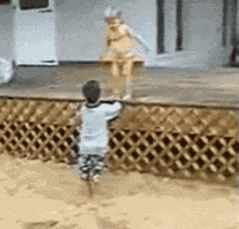 a boy is standing in front of a wooden fence watching a girl in a bikini jump into a pool .