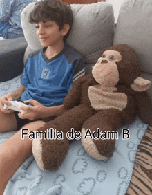 a boy playing a video game next to a stuffed monkey with the name familia de adam b on it