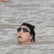 a woman wearing sunglasses is swimming in the water