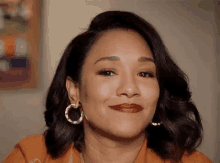 a close up of a woman wearing hoop earrings and red lipstick smiling .