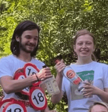 a man and a woman are standing next to each other holding bottles and signs that say 18 and 19 .