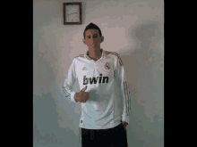 a young man wearing a white bwin jersey gives a thumbs up