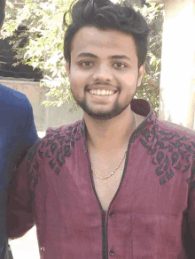 a man with a beard wears a maroon shirt with black embroidery