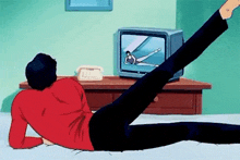 a man in a red shirt is laying on a bed while watching a tv show .