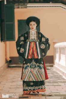 a woman in a traditional costume is standing in front of a building with the website www.hiepanhvietphuc.com