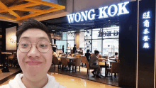 a man standing in front of a wong kok restaurant